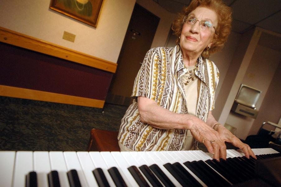 Bertha Shipton at the piano, glancing up mid-song