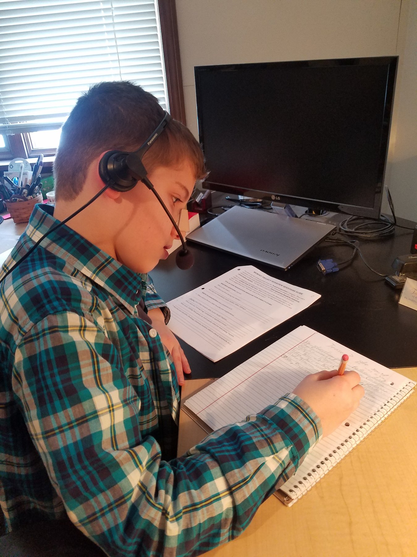 Judah wearing a headset, taking notes during the phone interview with Grandma Shipton